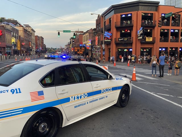 Event road closure on Broadway in downtown Nashville with cones, a message board and a police unit holding the intersection