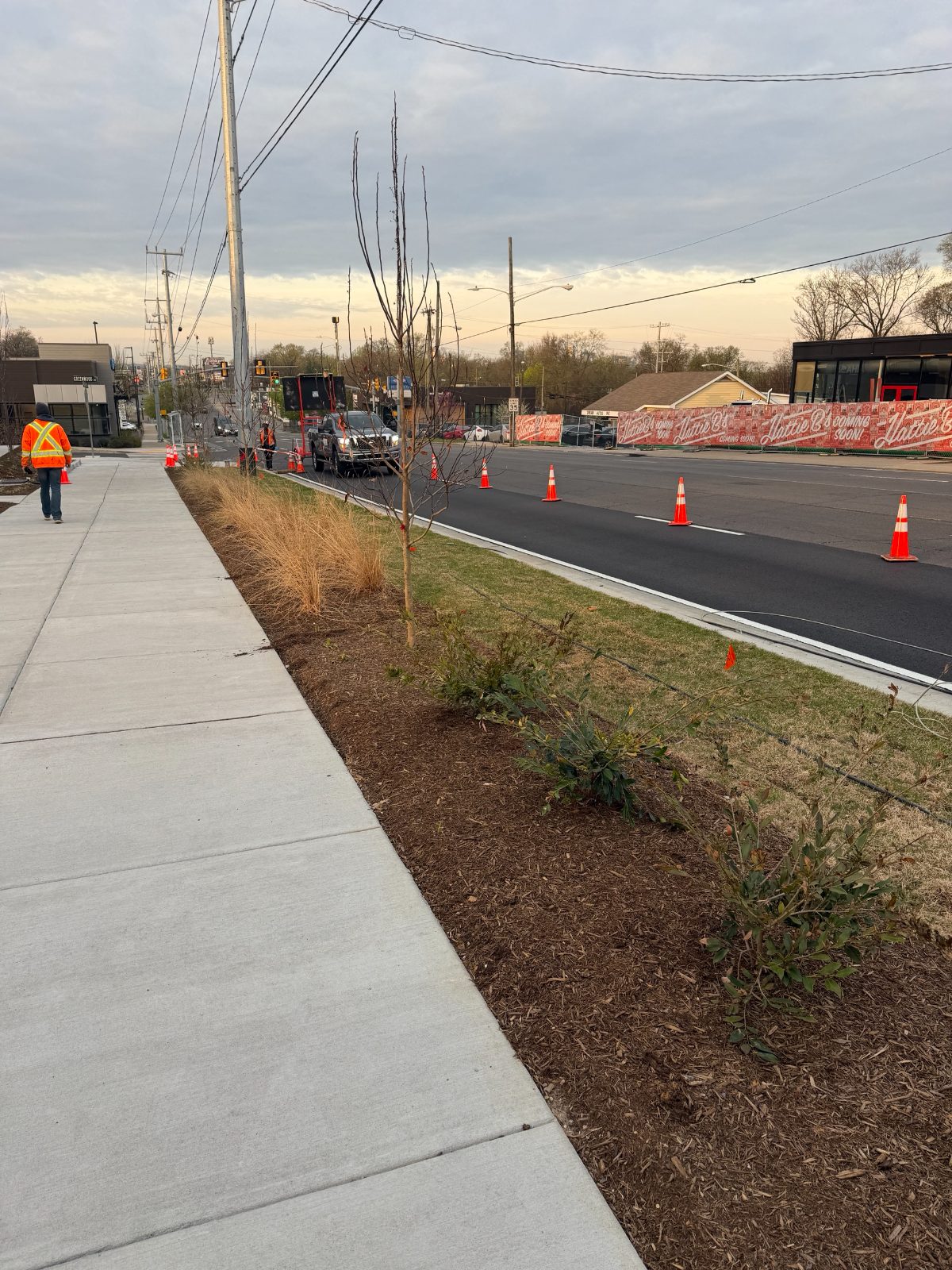 Lane closure with cones and an arrow board on a multi-lane East Nashville road during storm box repairs