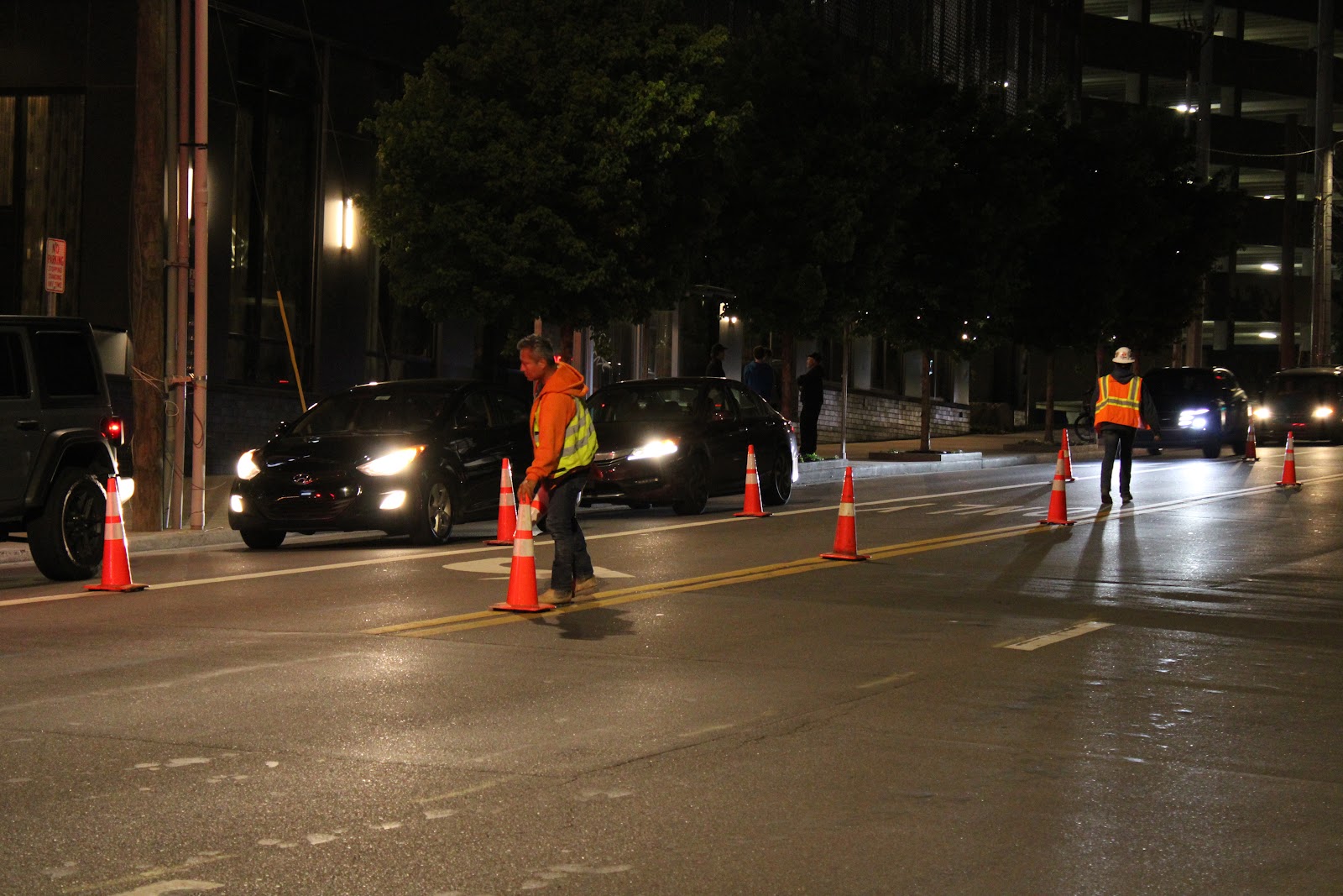 TTC crew member placing traffic cones at night while traffic passes on Broadway in Midtown Nashville
