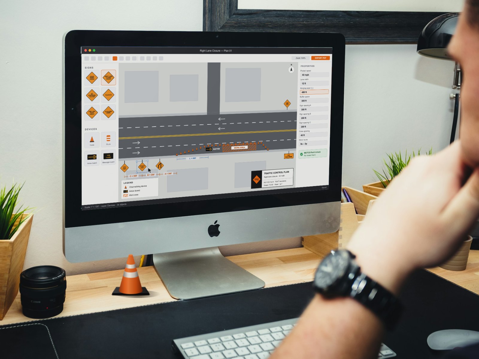 Person at a desk reviewing a traffic control plan for a right lane closure on a desktop computer, with a small traffic cone on the desk